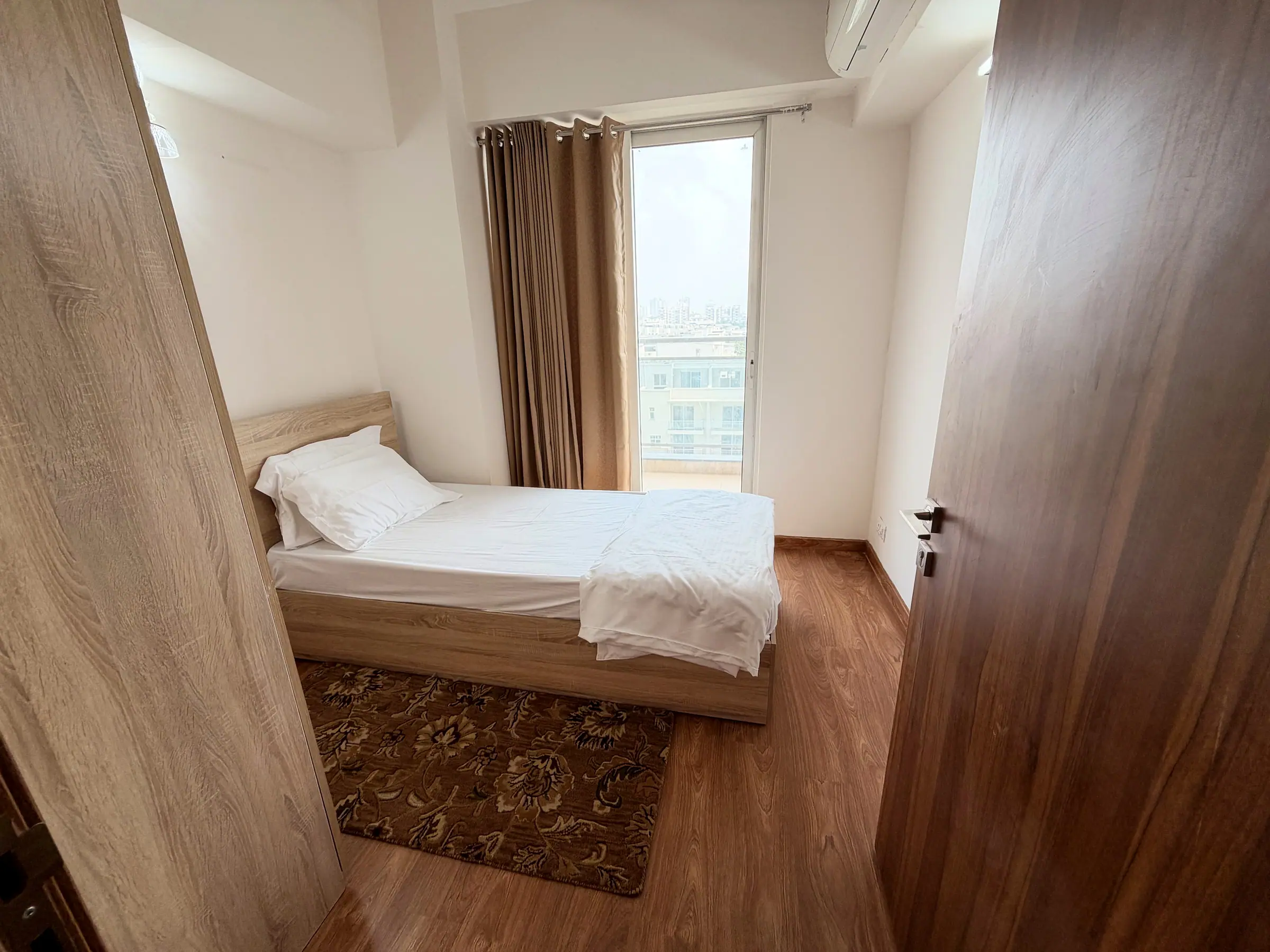Single bed and rug in bedroom two, seen from the doorway