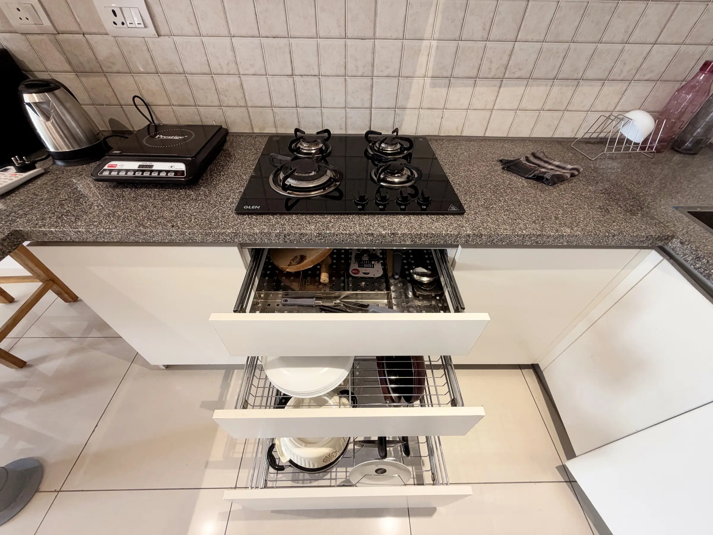 Gas hob and induction cooktop above pull-out drawers of crockery and cookware
