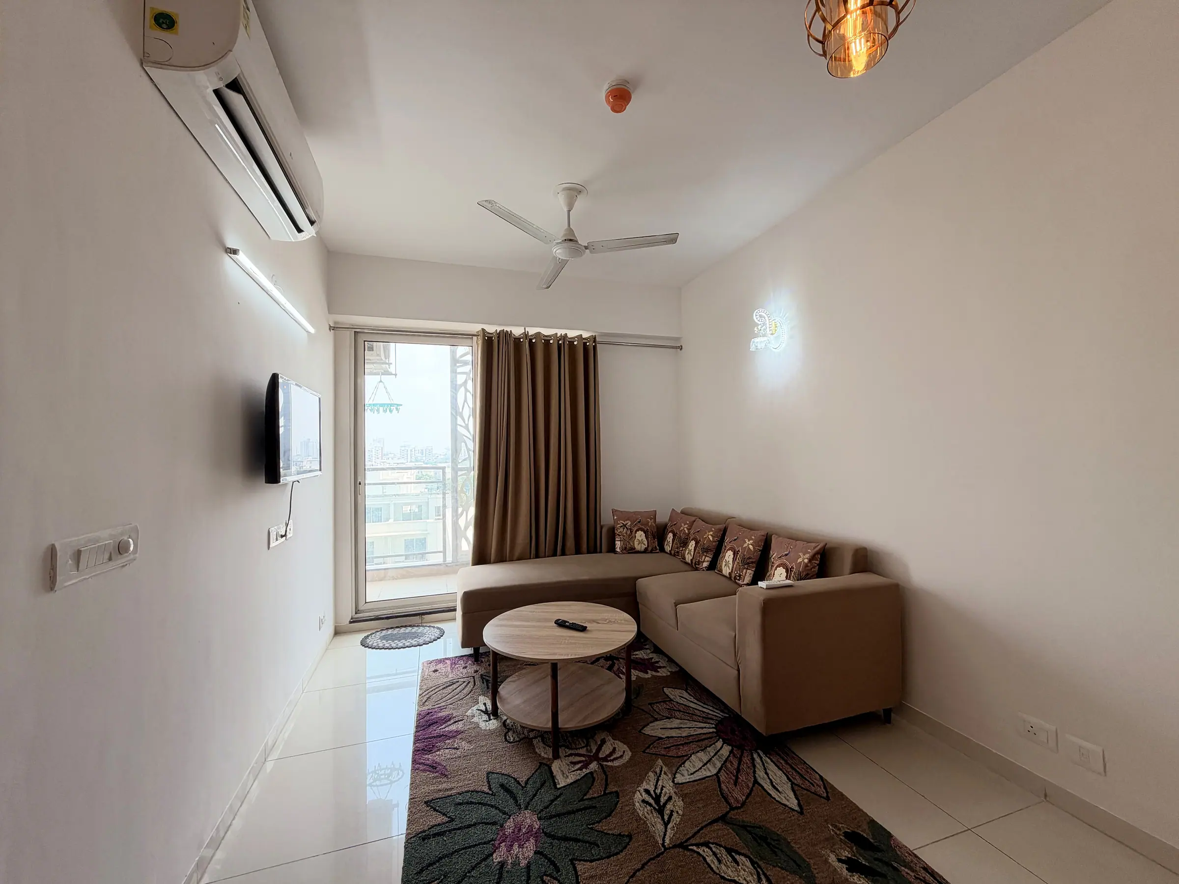 Elegant Suite living room with an L-shaped sofa, round coffee table, floral rug and wall-mounted TV