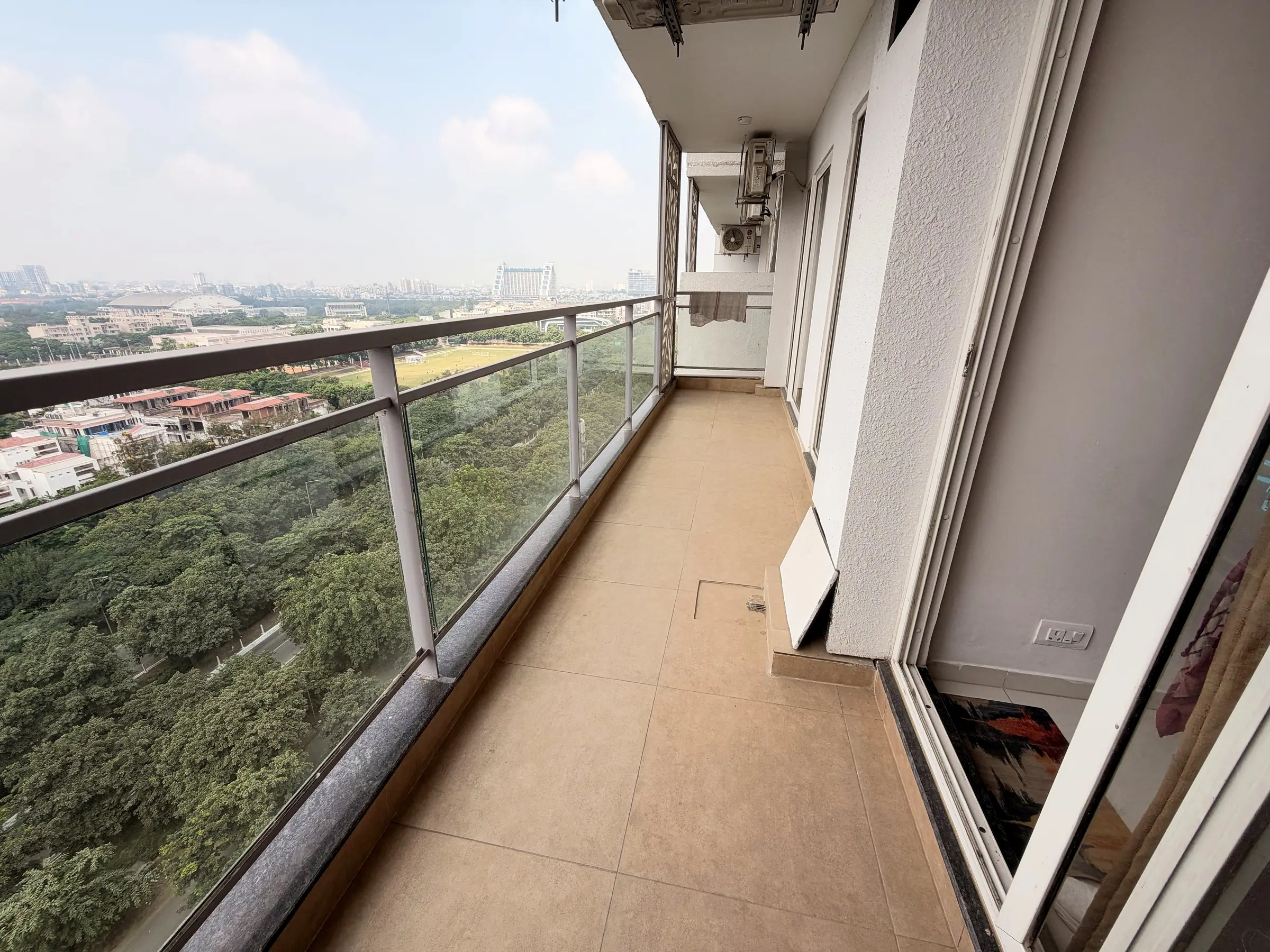 Long balcony with a glass railing above the green belt