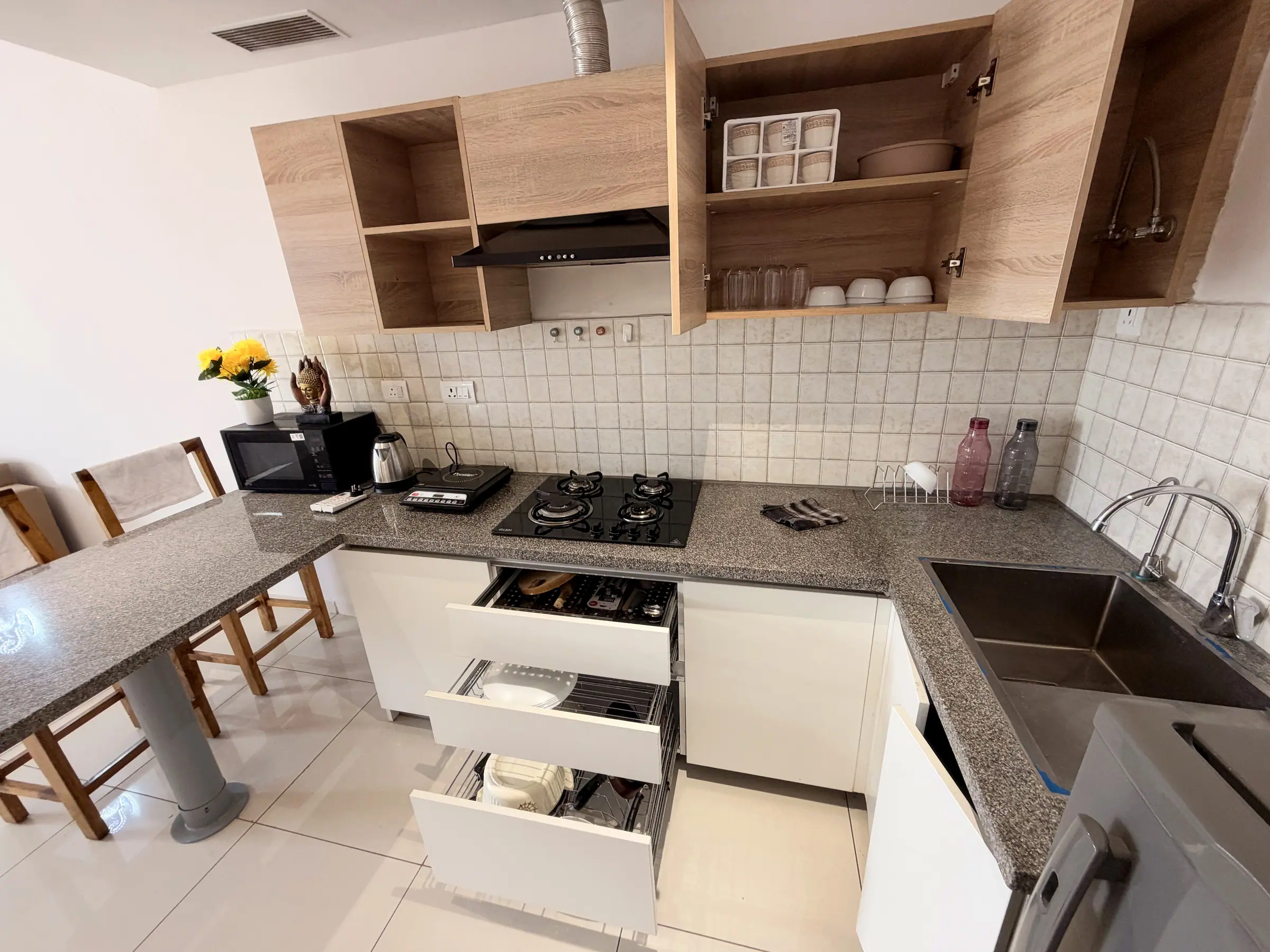 L-shaped kitchen with granite counters, gas hob, open oak shelves and pull-out drawers of crockery