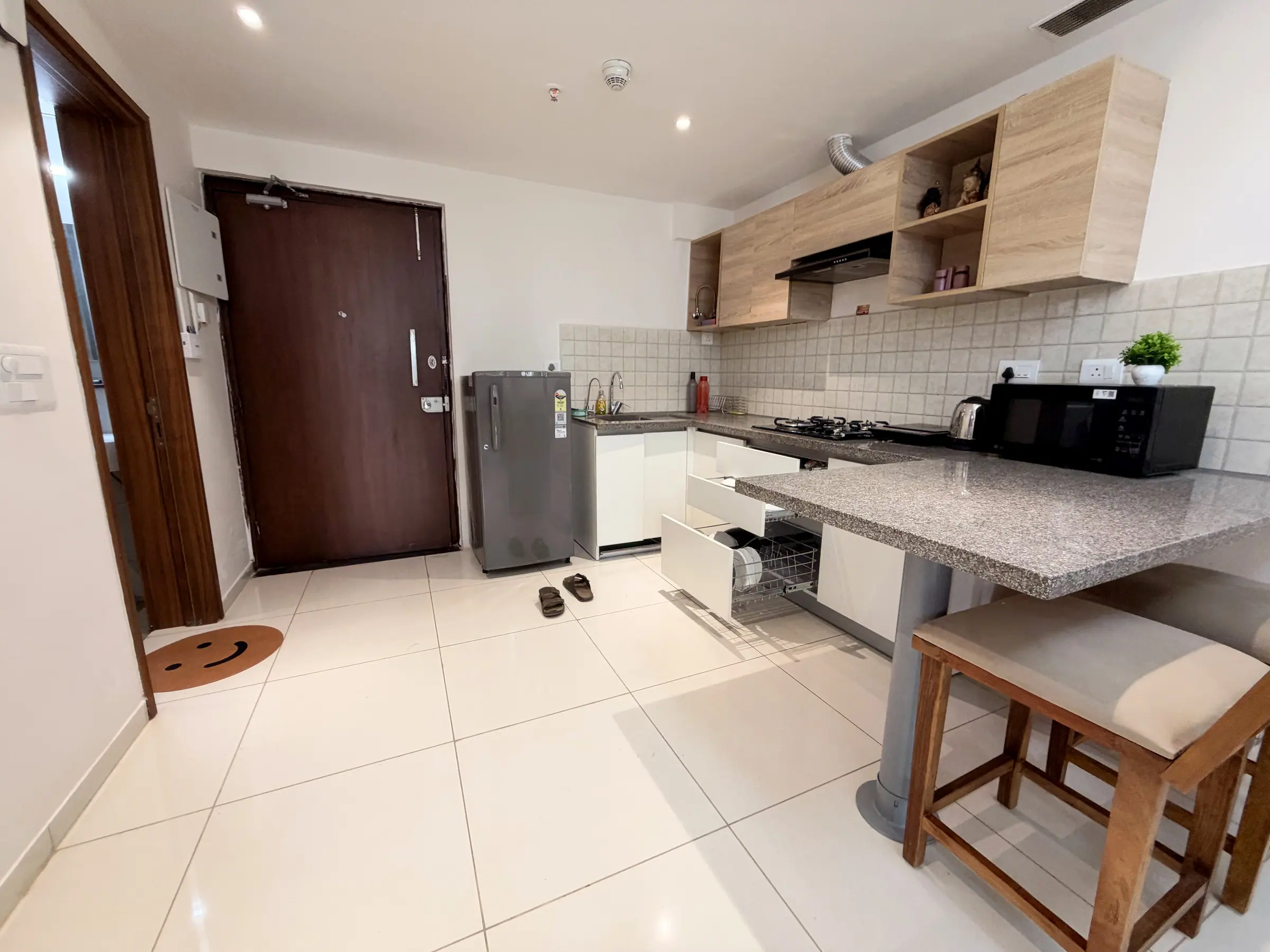 Front door, refrigerator and kitchen next to the granite breakfast bar