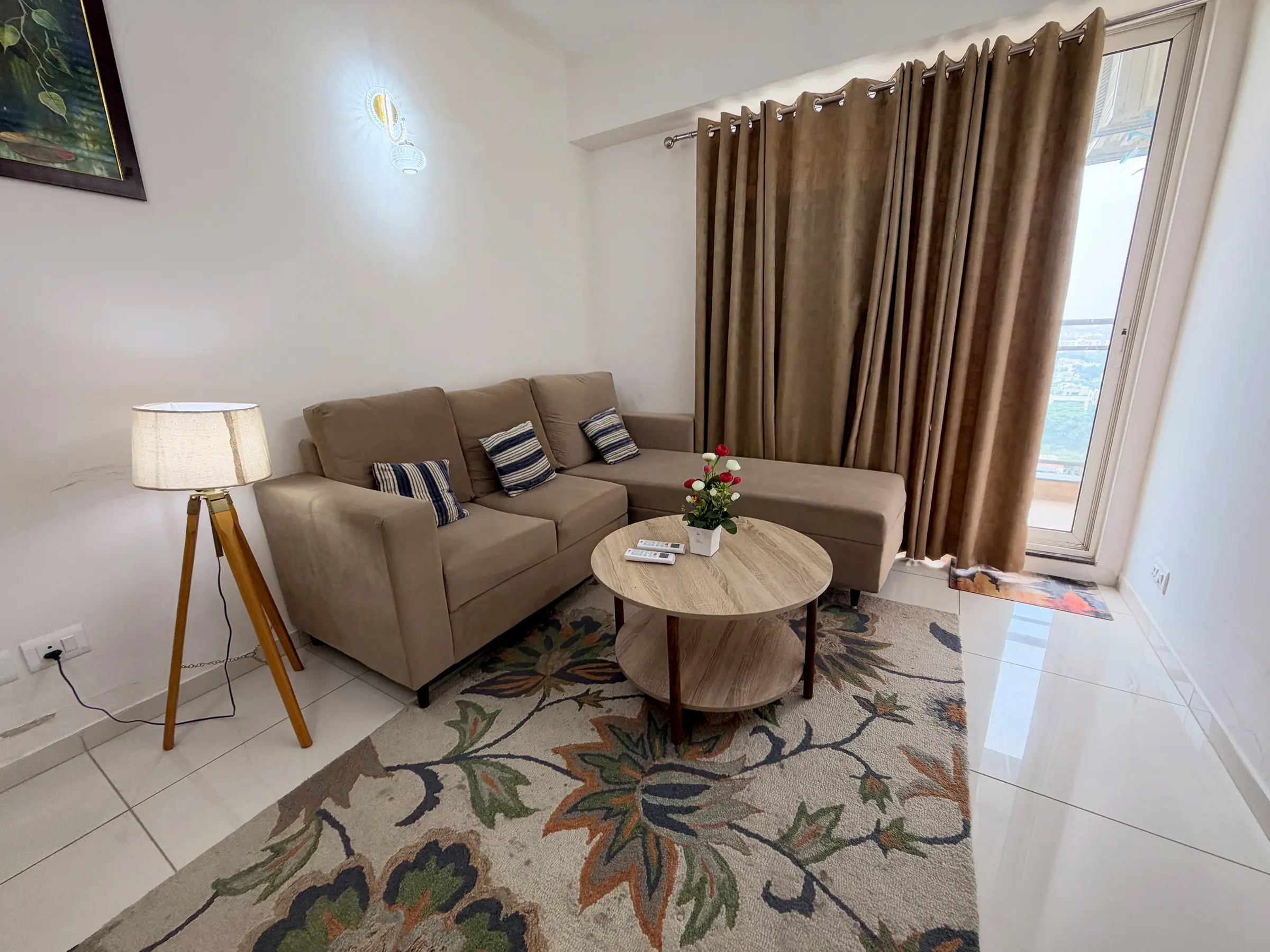 Sofa with striped cushions beside a tripod floor lamp and full-length curtains