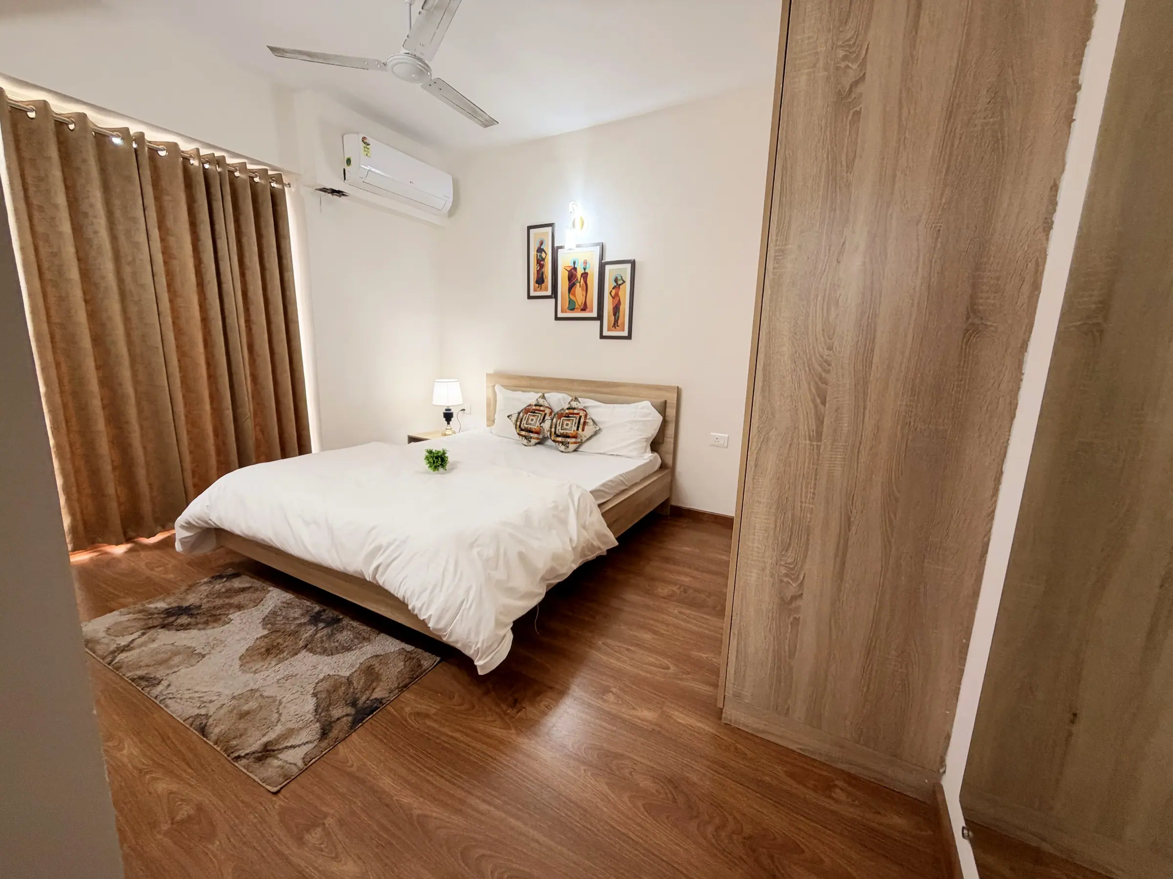 Main bedroom seen from the doorway, with the king bed, air conditioner and ceiling fan