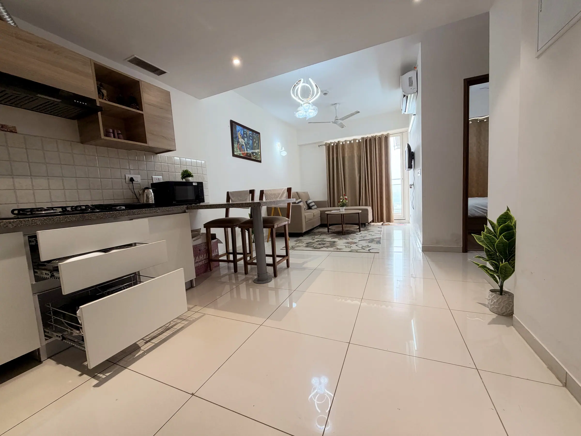Open-plan kitchen, breakfast bar and living room under a modern chandelier