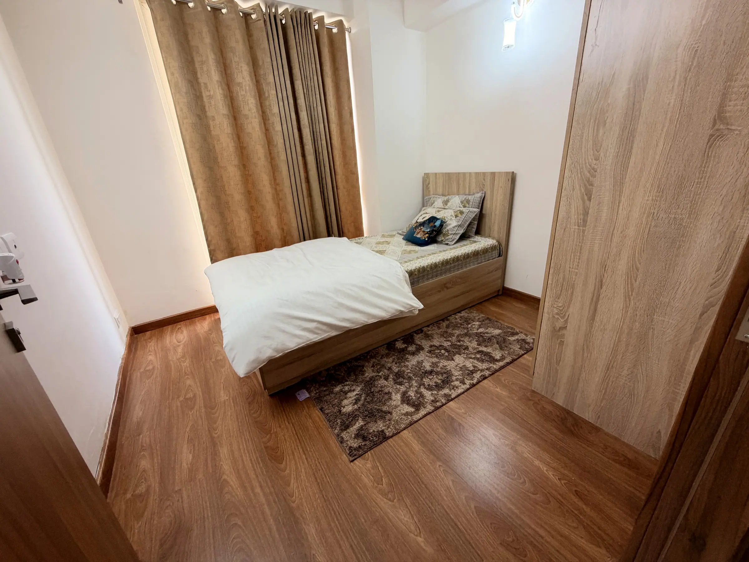 Second bedroom with a single bed by the curtained window